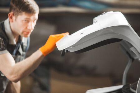 Man checks the car after polishing the body. Service restoration and maintenance of transport.
