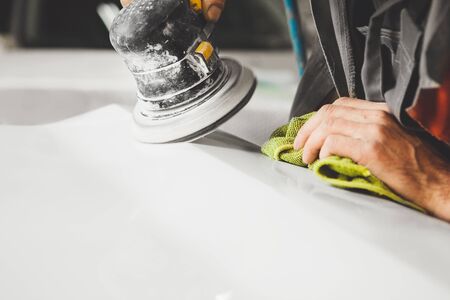 Auto mechanic grinds car part after painting before polishing, close-up.の写真素材