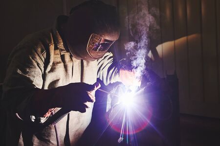 Male in mask welds metal steel. Welding of complex structures in the enterprise.