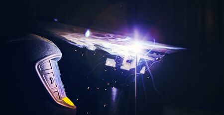 Close-up image of industrial worker at the factory welding steel structure on black background.の写真素材