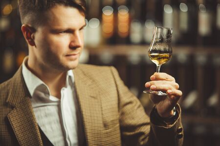 Portrait of male sommelier tasting whiskey at cellar.の写真素材