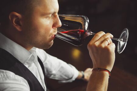 Sommelier tastes red wine by drinking beverage, man tasting alcoholic drinkの写真素材
