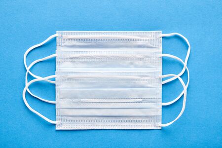 Close-up of medical masks on blue background, top view. Concept of mutual medical assistance and support.の写真素材