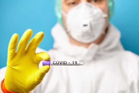 Express test on coronavirus. Scientist in protective coverall hold medical tube with test for a...