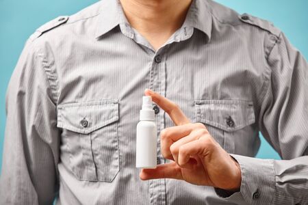 Close up view of antiseptic in human hands on blue background.