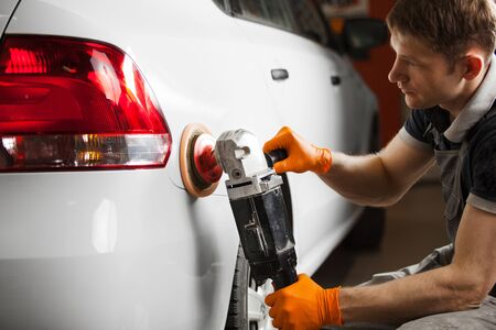 Polishing white car, close-up. A man polishes the automobile from scratches.の写真素材