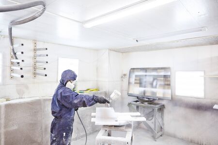 Staining wood with white spray gun, close-up shot. Application of flame retardant ensuring fire protection, airless spraying.の写真素材