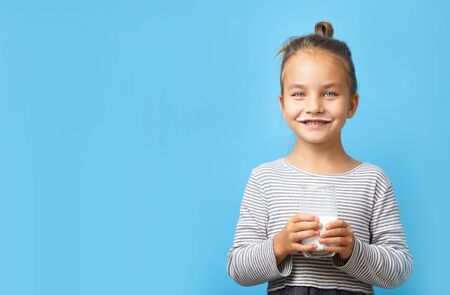 Child girl with glass of milk on blue isolated, image with free space for text.の写真素材