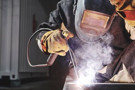 Welder working with welding on metal frames in an industrial plant. Industrial work.