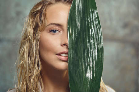 Woman face in profile with Natural nude make-up on a tropical leaf background.