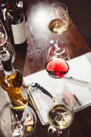 Wineglasses and wine bottles around clipboard on table