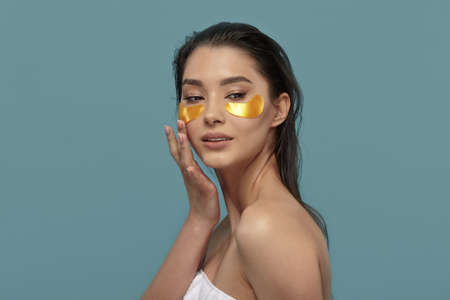 Beautiful happy lady using eye patches mask on blue.の写真素材