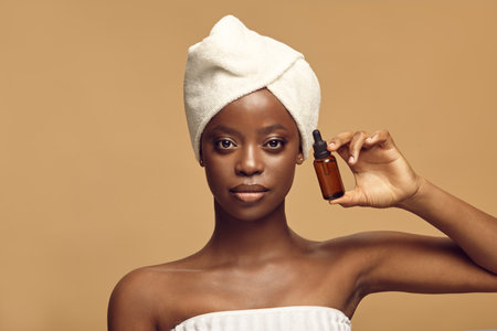 African American woman shows small cosmetic bottle.