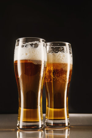 Golden brew with foam, bubbles filling tall glasses.の写真素材