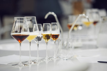 Various alcoholic beverages in glasses in white table in wine room. Sommelier school, professional certification, winemaking association.の写真素材