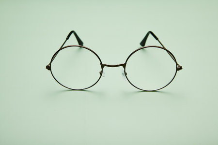 Open metal rimmed spectacles isolated on light-green.の写真素材