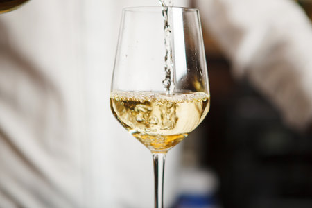 Closeup of glass with wine pouring by sommelier