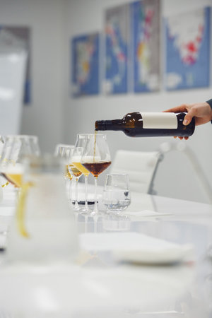Sommelier pouring unknown wine for blind tasting at table indoors, close up vertical photo.の写真素材