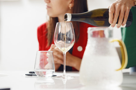 Close-up of sommelier pouring white wine into wine glass. Training and wine tasting.の写真素材
