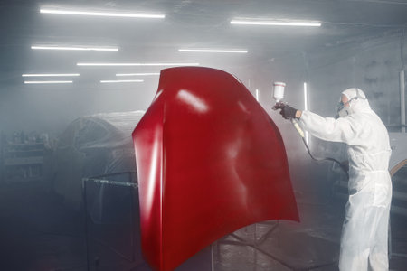 Professional car painter in chamber paints automobile bonnet.の写真素材