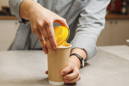 Baristas Secure Yellow Lid on Tall Paper Coffee Cup at Cafe Counter