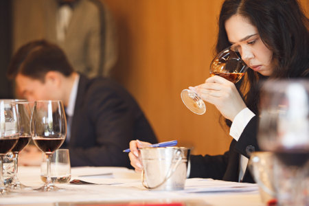 Female Wine Enthusiast Engaged in Smelling Analysis at Wine Tasting Exam.の写真素材