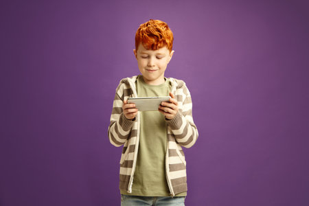 Waist Portrait of Red Headed Child Boy Passionate Playing Game on Smartphone, Unable to Break Away...