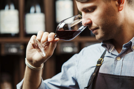 Bokal of red wine on background, male sommelier appreciating drinkの写真素材