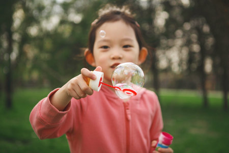 Young Girl Blowing Bubbles in Summer Parkの写真素材