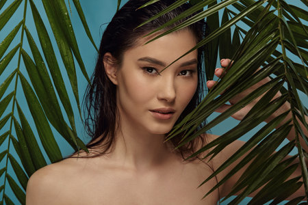 Asian beautiful girl standing among tropical plants leaves.の写真素材