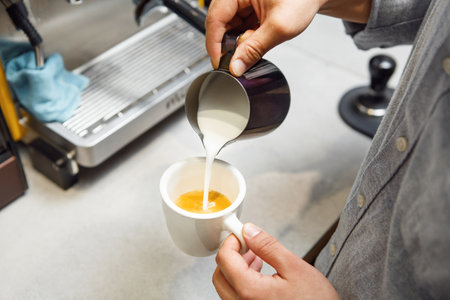 Barista Expertly Pours Steamed Milk Into Espresso to Craft Perfect Cappuccinoの写真素材
