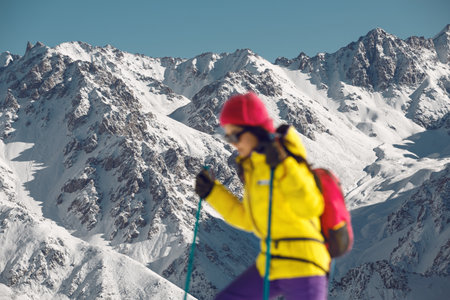 Blurred Woman Ascends Snow-Covered Slope Under Bright Winter Sunlight in Mountainous Terrainの写真素材