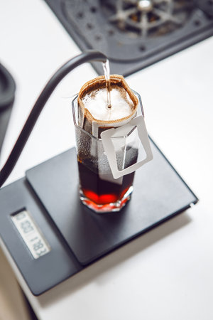 Hot Water is Poured Over a Coffee Drip Bag Resting on Scale for Precise Brewing Measurement, Close...