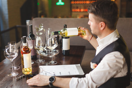 Sommelier sits at table with accessories for wine degustation.