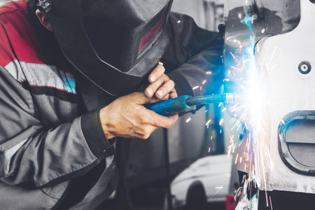 Working with carbon dioxide welding to fix metal body. Repair service worker recovery damaged car. Welder, weld.の写真素材