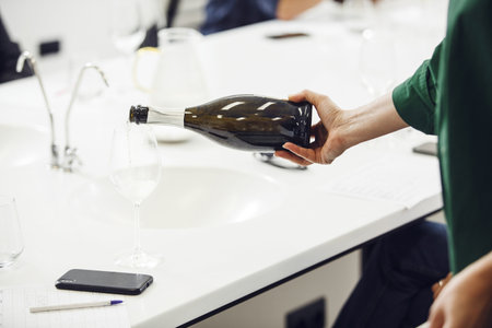 Bartender pours sparkling wine into glasses for the participants of the training held at the...