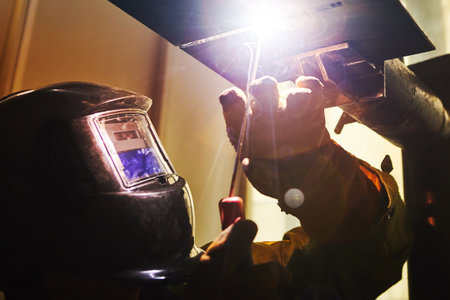 Male in face mask welds with welding