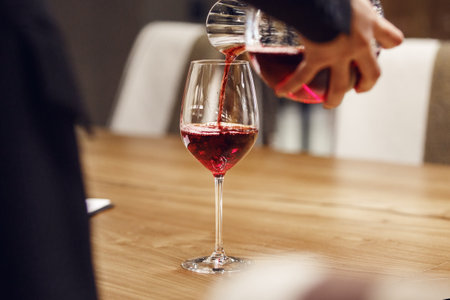 Bartender pouring red wine from decanter to the glass, close up image.の写真素材