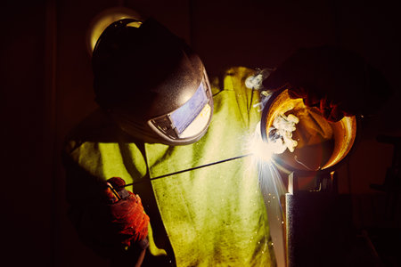 Welder in protective mask welds steel constructions.