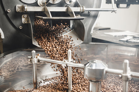 Close up of Pouring Out Hot Freshly Roasted Coffee Beans From Roasting Drum to Cooling Hull of Industrial Roastery Machineの写真素材
