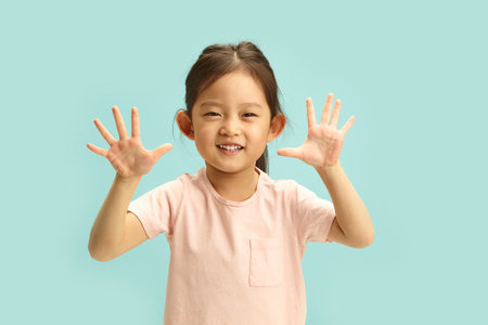 Cheerful Asian Child Celebrates with a High-Five Gesture. Exuberant Youngster Radiates Happiness on Isolated Backgroundの写真素材