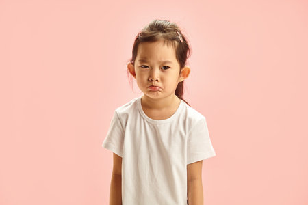 Frustrated Little Asian Girl Pursing her Lips from Resentment with a Gloomy Expression on Face...
