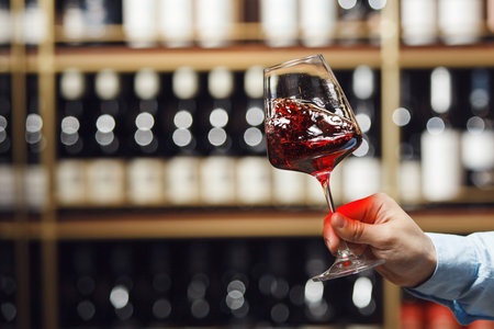 Sommelier Expertly Swirling Glass of Red Wine in Close-Up Shot Against Cellar Background with a Free Copy Spaceの写真素材