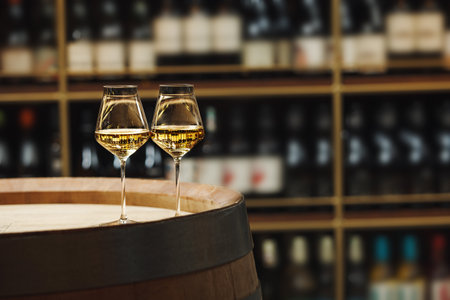 Two Champagne Glasses Resting on Wooden Barrel in Cellarの写真素材