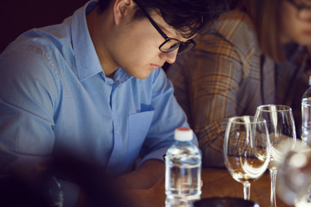 Man Analyzing White Wine Glasses Sitting Table During Passes Training for Sommelierの写真素材