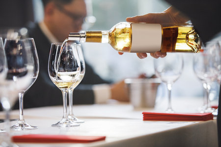Close-up Sommelier Pours White Wine in Glass During Training Eventの写真素材