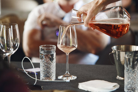 Sommelier school. Professional wine waiter pouring wine into decanter to the glasses during alcoholic beverages training for staff. Blind wine degustation.の写真素材