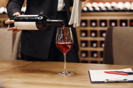 Sommelier Pouring Red Wine From Bottle to the Glass Being in Cellar, Close Up.の写真素材