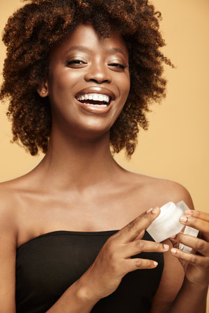 Smiling model doing daily skin care routine at home.