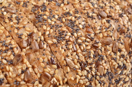 Slices whole grain bread decorated with natural cereals. Macro with shallow dof.